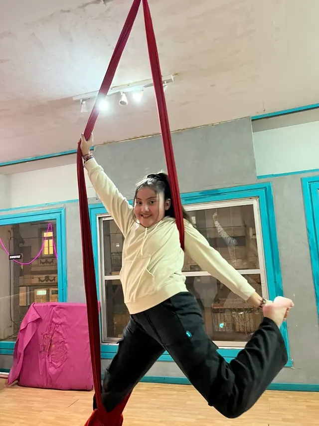 Alumna en el Estudio Melani Mitchell, en estrella sobre la tela roja, con un pie enganchado y el otro estirado