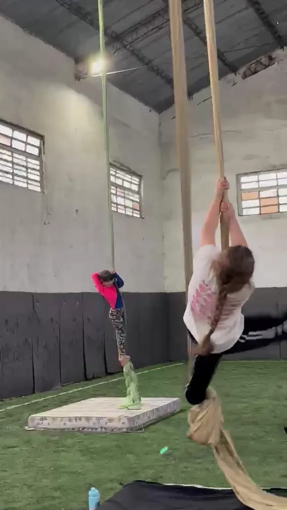 Clase infantil de telas en el Gimnasio Alma: alumnas se balancean y suben por las telas de colores sobre colchonetas, en la cancha techada